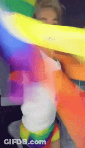 A Person Is Holding A Rainbow Flag Over Their Head GIF