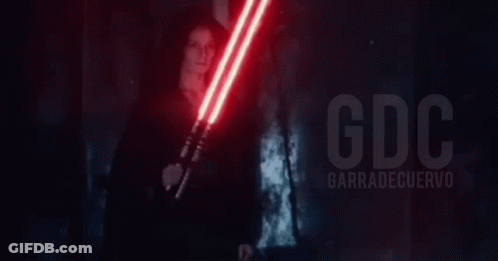 A Person Is Holding A Red Light Saber In Their Hand In A Dark Room . GIF