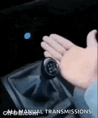 A Person Is Holding A Shifter In A Car And Pressing A Button . GIF