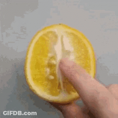 A Person Is Holding A Slice Of Lemon With Their Finger On It GIF