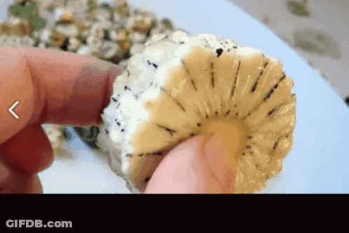 A Person Is Holding A Slice Of Pineapple With A Arrow Pointing To The Left GIF