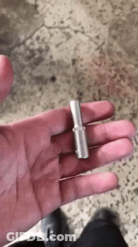 A Person Is Holding A Small Piece Of Metal In Their Hand . GIF