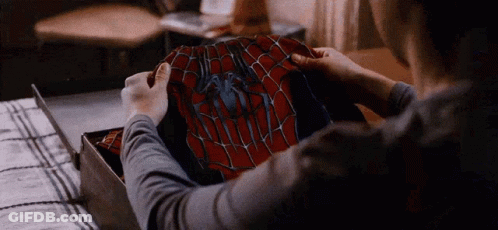 A Person Is Holding A Spider Man Costume In Their Hands . GIF