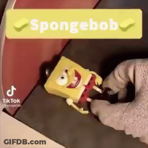 A Person Is Holding A Spongebob Toy In Their Hand And A Sign That Says Spongebob . GIF