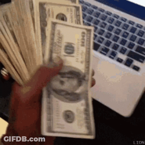 A Person Is Holding A Stack Of 100 Dollar Bills In Front Of A Laptop . GIF