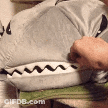 A Person Is Holding A Stuffed Animal That Looks Like A Shark . GIF