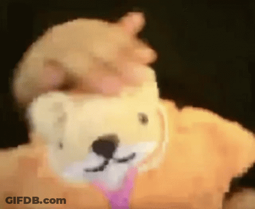 A Person Is Holding A Stuffed Animal That Looks Like A Teddy Bear With A Pink Tie Around Its Neck . GIF