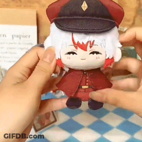 A Person Is Holding A Stuffed Doll Wearing A Hat And A Red Coat GIF