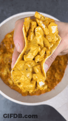 A Person Is Holding A Taco In Front Of A Bowl Of Sauce GIF