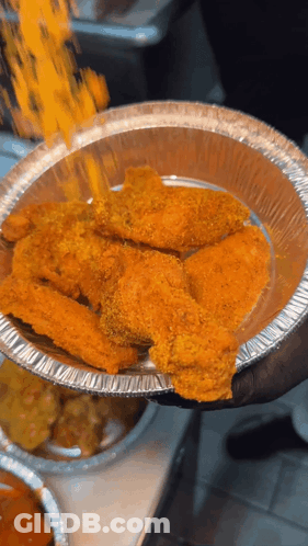 A Person Is Holding A Tin Foil Container Of Chicken Wings GIF