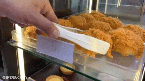 A Person Is Holding A Tong Over A Display Case Of Food GIF