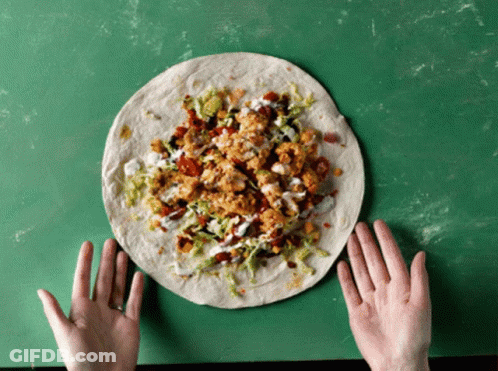 A Person Is Holding A Tortilla With A Lot Of Toppings GIF