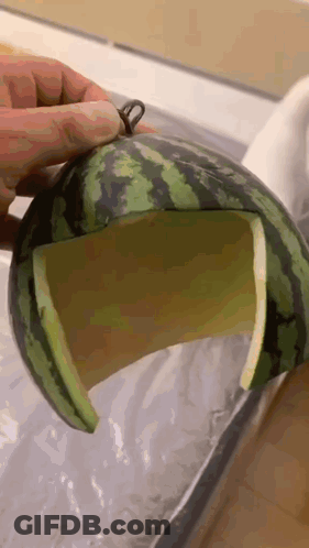 A Person Is Holding A Watermelon With A Hole In It GIF