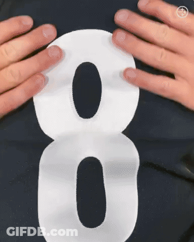 A Person Is Holding A White Number 8 On Their Shirt GIF