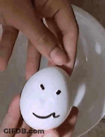 A Person Is Holding An Egg With A Face Drawn On It . GIF