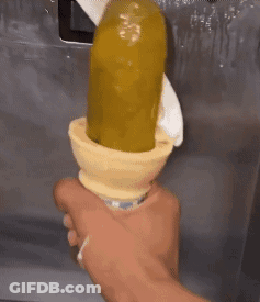 A Person Is Holding An Ice Cream Cone That Has A Pickle In It . GIF