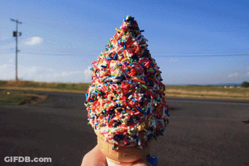 A Person Is Holding An Ice Cream Cone With Sprinkles On It GIF