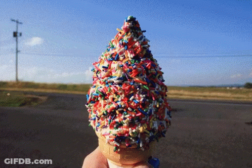 A Person Is Holding An Ice Cream Cone With Sprinkles On It GIF