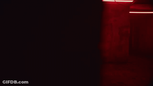 A Person Is Holding Something In Their Hands In A Dark Room With Red Lights GIF