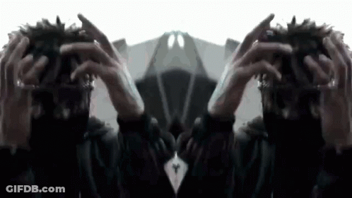 A Person Is Holding Their Hands To Their Head And Looking At A Mirror . GIF