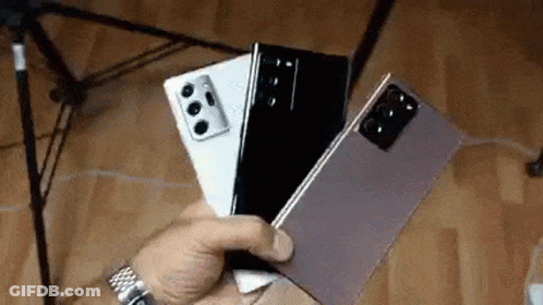 A Person Is Holding Three Cell Phones In Their Hand . GIF
