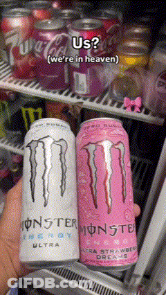 A Person Is Holding Two Cans Of Monster Energy Drinks In Front Of A Fridge GIF