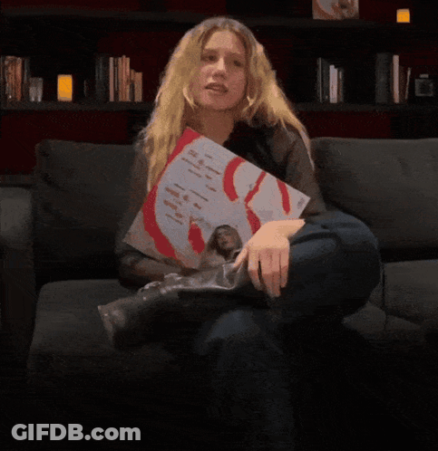 A Person Is Holding Up A Picture Of A Man With A Red S On His Chest GIF