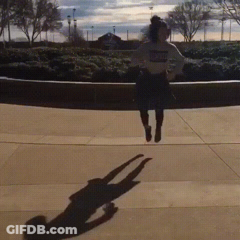 A Person Is Jumping In The Air And Their Shadow Is Visible . GIF