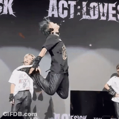 A Person Is Jumping In The Air In Front Of A Sign That Says " Act Love " GIF