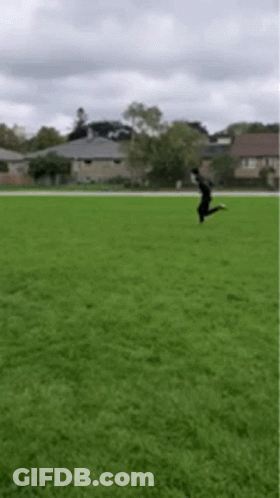 A Person Is Jumping In The Air On A Grassy Field . GIF