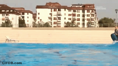 A Person Is Jumping Into A Swimming Pool With A Building In The Background That Says ' Allianz ' GIF