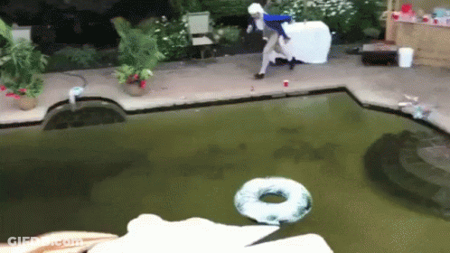 A Person Is Jumping Into A Swimming Pool With A Donut Floating In It GIF