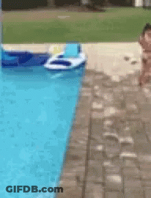 A Person Is Jumping Into A Swimming Pool With A Raft In The Water GIF