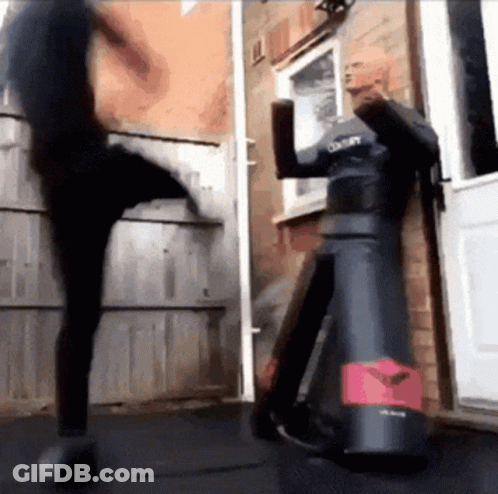A Person Is Kicking A Dummy That Says Century On It GIF
