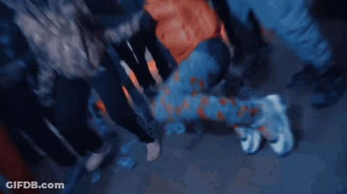 A Person Is Kneeling Down In A Crowd Of People Wearing Adidas Pants GIF