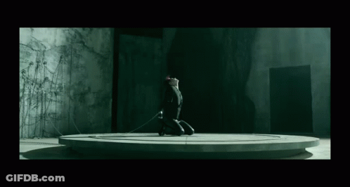 A Person Is Kneeling Down In A Dark Room With A Rope Around Their Neck GIF