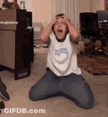 A Person Is Kneeling Down With Their Hands On Their Head . GIF