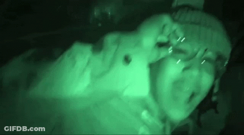 A Person Is Laying Down In A Dark Room With A Green Light Coming Out Of Their Eyes . GIF
