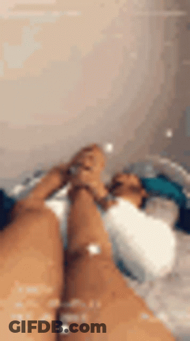 A Person Is Laying In A Bathtub With Their Feet Up . GIF
