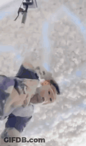 A Person Is Laying In A Pile Of White Foam . GIF