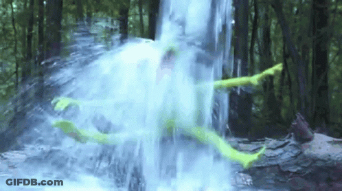 A Person Is Laying In A Waterfall In The Woods GIF