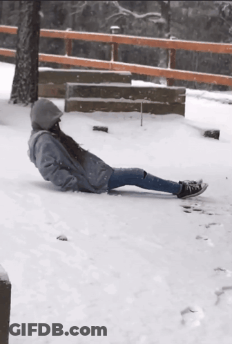 A Person Is Laying In The Snow With A Fence In The Background GIF