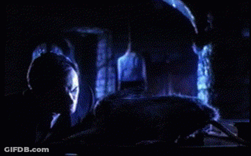 A Person Is Laying On A Bed In A Dark Room With A Blue Light Behind Them GIF