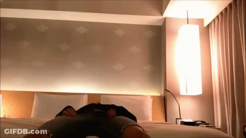 A Person Is Laying On A Bed In A Room GIF