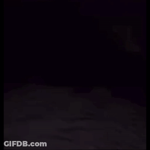 A Person Is Laying On A Bed With A Ghost Behind Them . GIF
