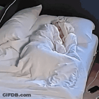 A Person Is Laying On A Bed With White Sheets GIF