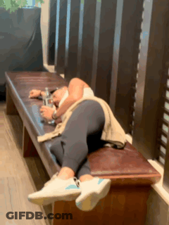 A Person Is Laying On A Bench With A Bottle Of Water In Their Hand . GIF