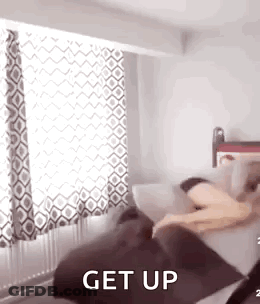 A Person Is Laying On A Couch In A Bedroom With The Words `` Get Up '' Written On It . GIF