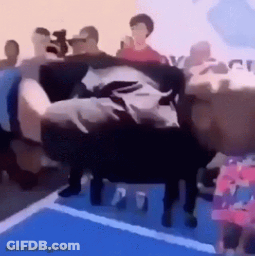 A Person Is Laying On A Couch In Front Of A Crowd . GIF