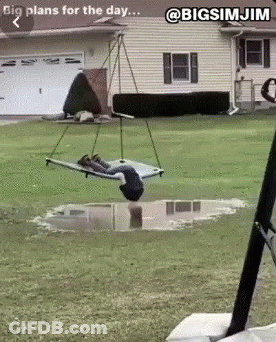 A Person Is Laying On A Hammock In A Puddle In A Yard . GIF
